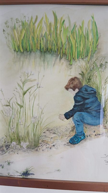 Watercolour of a child crouching by reeds at the water's edge